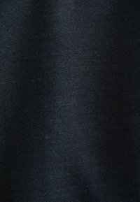 Tissu en denim bleu foncé avec une texture lisse, montrant un subtil motif de tissage sergé et un léger éclat. Aucuns accents ou éléments en métal notables.
