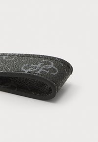 Black leather strap with a textured surface, featuring subtle gray patterns and rounded edges. Slim profile, designed for versatility.