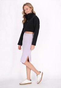 Jachetă scurtă neagră cu fermoar, fustă midi de culoare mov deschis cu despicături laterale, asortată cu teniși albi și gri. Materiale netede, design casual.