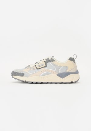 Sneakers in grigio chiaro, crema e accenti pastello. Materiali in mesh e suede, suola spessa, punta arrotondata e sistema di allacciatura. Etichetta di branding distintiva.