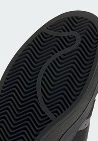 Μαύρη σόλα παπουτσιού από καουτσούκ με κυματιστό σχέδιο πέλματος· υφή στην επιφάνεια και καμπυλωτές λεπτομέρειες. Κατασκευασμένη για πρόσφυση και ανθεκτικότητα.