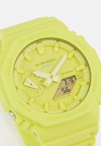 Montre G-SHOCK avec un bracelet en silicone jaune vif, dotée d'un boîtier rond, d'un affichage analogique-numérique et de grands index horaires. Résistante à l'eau jusqu'à 20 BAR.