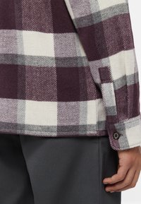 Tjekket flannel skjorte i burgundy, grå og hvid. Har knapmansjetter og blød tekstur, med en afslappet pasform og diagonal mønster.