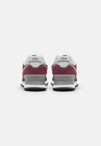 Bordeaux színű velúr sneaker fehér részletekkel, párnázott bokarésszel és nyelvvel, hálós panelekkel, valamint látható varrású gumitalppal.