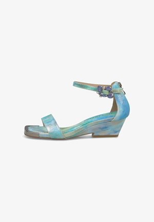 Sandalia cuña baja metálica en azul claro con tira en el tobillo y hebilla decorativa con piedra preciosa púrpura, puntera cuadrada y puntera plateada.