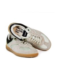 Zapatillas de ante gris claro con acentos negros y suelas de goma natural. Las características incluyen un collar acolchado, cierre de cordones en la parte delantera y paneles laterales texturizados.