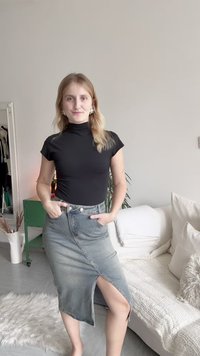 Fekete, rövid ujjú, félmagas nyakú felső párosítva egy világoskék, farmer anyagú, köntöshöz hasonló szoknyával, amely oldalhasítékkal és övbújtatókkal rendelkezik.