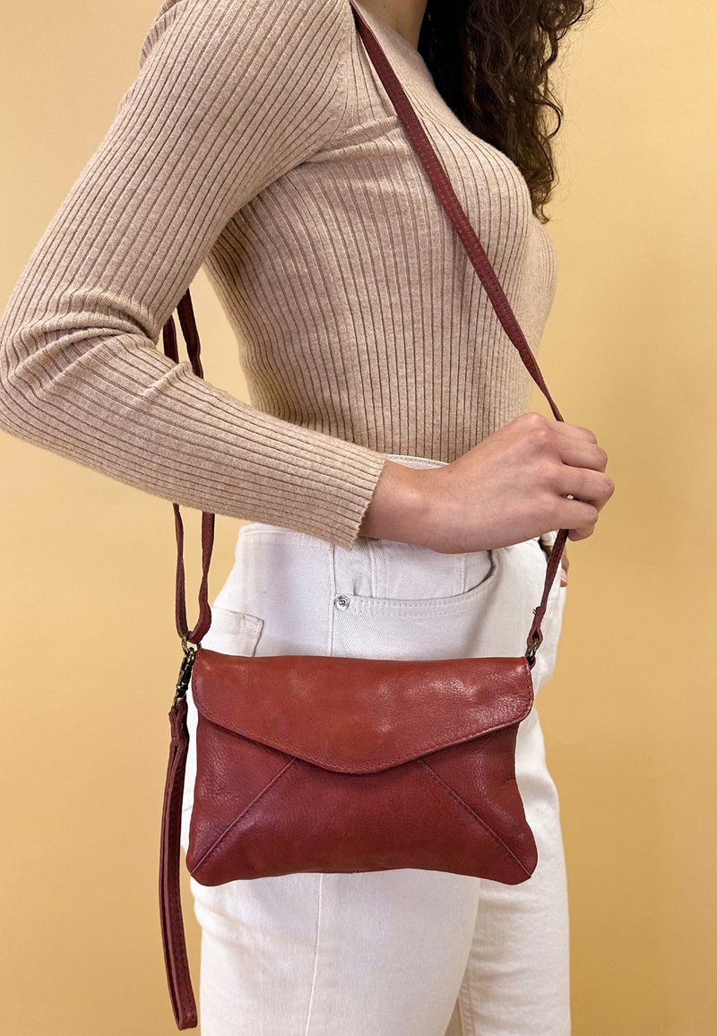 Borsa a tracolla rossa in pelle con superficie testurizzata e leggermente lucida, dotata di un flap in stile busta e di una tracolla regolabile.