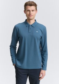 Langærmet polo skjorte i teal stof, med en klassisk krave, tre knapper og et lille logo på venstre bryst. Glat tekstur.