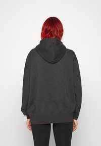 Mörkgrå bomullshuvtröja med stor huva och lös passform. Har ribbade ärmkanter och nederkant, med en mjuk textur och utan synliga mönster.