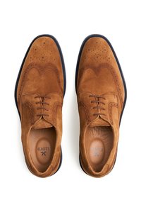 Bruine suede dresschoenen met een wingtip-ontwerp, voorzien van geperforeerde details, bruine veters en een contrasterende marineblauwe zool.