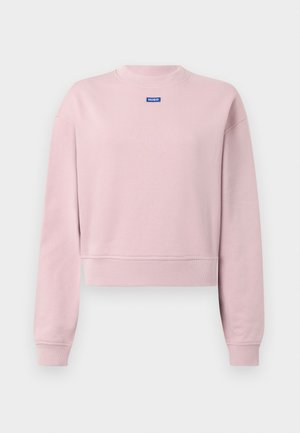 Sweatshirt rose clair court en matière douce avec encolure et poignets côtelés. Présente une étiquette logo bleue près du col. Design simple.