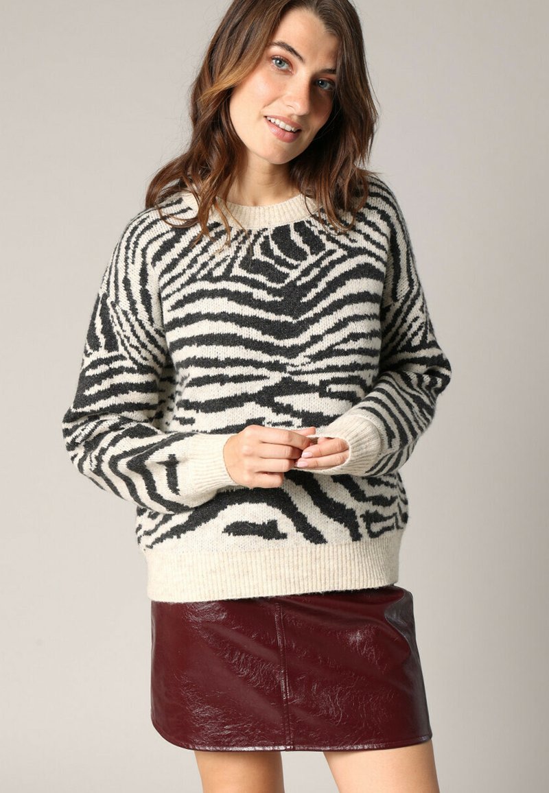 Pull à rayures noir et blanc en tricot doux, doté d'un col rond et de poignets côtelés, associé à une mini-jupe en cuir bordeaux brillant.