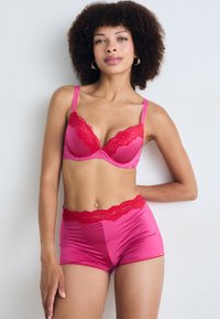 Fuchsia lingerieset met een gepadded beha met rode kanten rand en bijpassende satijnen shorts met kanten tailleband, ontworpen met een gladde stof.