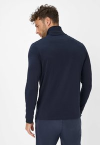 Marineblauer Langarm-Pullover mit hohem Kragen und glatter Textur. Verfügt über Seitenschlitze am Saum für zusätzlichen Komfort und Beweglichkeit.