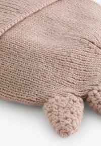 Jouet en peluche tricoté en fil de laine rose pâle, doux ; présente des oreilles arrondies et un motif de points texturé. Surface lisse avec une apparence confortable.