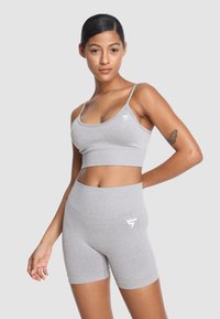 Szary zestaw sportowy: stanik w kształcie biustonosza oraz szorty z wysokim stanem, wykonany z miękkiego, elastycznego materiału; na górze i szortach znajduje się logo w kolorze białym.
