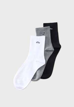 Drei Paar Crew-Socken in Weiß, Grau und Schwarz, jeweils mit einem kleinen ovalen Logo nahe dem Bündchen, überlappend auf einem schlichten Hintergrund angeordnet.