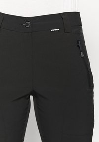 Pantalon d'extérieur noir à la taille avec poche zippée, fermeture à bouton, passants de ceinture et une petite étiquette de marque sur le côté droit avant.