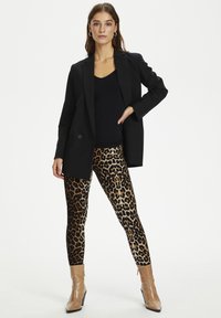 Crna blazer jakna, crni top bez rukava i tajice s uzorkom leoparda. Suede, čizmice do gležnja s potpunim vrhom u bež boji s elegantnim završetkom.