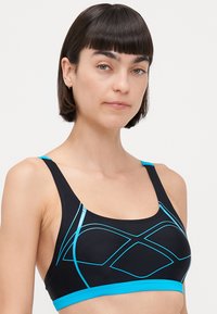 Soutien-gorge de sport noir avec des accents bleu clair et un design géométrique. Fabriqué à partir d'un matériau lisse, il possède des sangles épaisses et une forme qui offre un bon maintien.