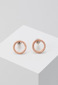 Naušnice u obliku kružnice od ružičastog zlata s brušenom teksturom, sa srebrnim držačima i minimalističkim dizajnom. Elegantne i lagane za jednostavno nošenje.