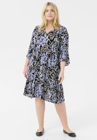 Vestido negro con estampado floral y animal en tonos de azul y crema. Presenta un escote en V, mangas de tres cuartos acampanadas y una falda de volantes.
