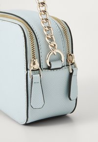 Light blue textured handbag with gold hardware, featuring dual zippers and a chain strap. Accents include black edges and small tags.