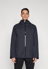 Marineblaue wasserdichte Jacke mit hohem Kragen, Frontreißverschluss, verstellbare Kapuze und strukturierten Akzenten an den Bündchen für einen sicheren Sitz.