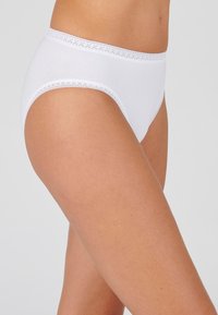 Witte katoenen hipster slips met een golvende kantafwerking langs de tailleband, een gladde textuur en een eenvoudig ontwerp.