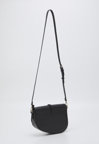 Black leather crossbody bag with a rounded bottom, flat top flap, adjustable strap, and gold-tone hardware accents. Smooth texture and minimalist design.