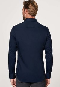 Marineblauwe overhemden met lange mouwen, voorzien van een klassieke kraag, een gladde textuur en een afgeronde zoom. Minimalistisch ontwerp zonder zichtbare patronen.