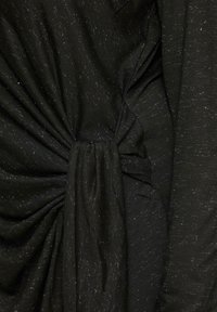 Schwarzer Stoff mit einem subtilen Glanz, ausgestattet mit einem verdrehten Detail an der Taille. Die Textur enthält feine, schimmernde Fäden für zusätzlichen Interesse.