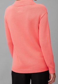 Korallenfarbener Strickpullover mit Kragen, mit strukturierten Oberflächen und geripptem Saum, von hinten präsentiert, mit langen Ärmeln und lockerer Passform.