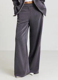 Pantaloni grigi a gamba larga in tessuto morbido con un motivo a puntini bianchi di piccole dimensioni. Presentano una cintura piatta e un design sobrio con linee pulite.