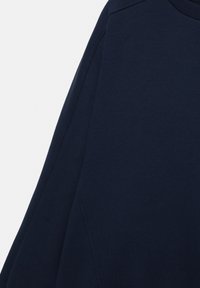 Zbliżenie na długorękawową odzież w ciemnogranatowym kolorze, ukazujące fakturę tkaniny oraz szczegóły szwów na rękawie i ramieniu.