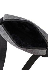 Šedá látková taška přes rameno s texturovaným povrchem, horním zipem a černým interiérem. Disponuje pevným nastavitelným popruhem.
