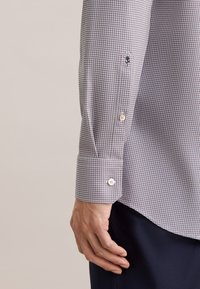 Overhemd met lange mouwen, voorzien van een klein ruitpatroon in marineblauw en wit, met knoopmanchetten en een gladde katoenen textuur.