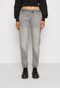 Grå denim joggerbukser med elastisk linning, snor og mansjetter på ankler, stylet med svarte snørebåndsstøvler. Teksturert stoff med lett falming.