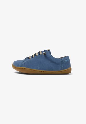 Zapatillas de ante azul con cordones beige, perfil bajo, suela de goma, detalles de costura y un parche de marca en el talón.
