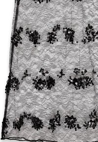 Melnā mežģīņu auduma, kas ar viļņotu rakstu, izrotāts ar spīdīgiem melniem un sudrabainiem spīguļiem, kas izvietoti ziedu grupās visā virsmā.