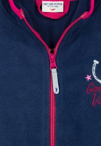Navy fleece jacket met een voorrits, roze ritstrekkertje en roze accenten. Kenmerken zijn de geborduurde tekst "Good Vibes" en sterontwerpen.