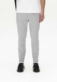 Grå, slim-fit byxor i texturerat tyg, med flat front och framfickor. Bärs med svarta skor med detaljer i form av fransar.