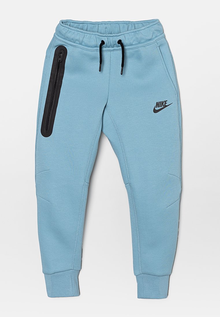 Jasnoniebieskie dresy Nike z elastyczną talią, czarnymi sznurkami, boczną kieszenią na zamek oraz zwężającymi się nogawkami. Gładki materiał i subtelne akcenty.