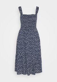 Marineblauwe bloemenjurk met witte patronen, heeft een smock-bodice, brede schouderbanden en een gelaagd rokdesign.