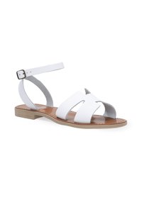 Hvide læder sandaler med flad sål, der har overlapende stropper og en ankelrem med en metal spænde. Glat tekstur og minimalistisk design.