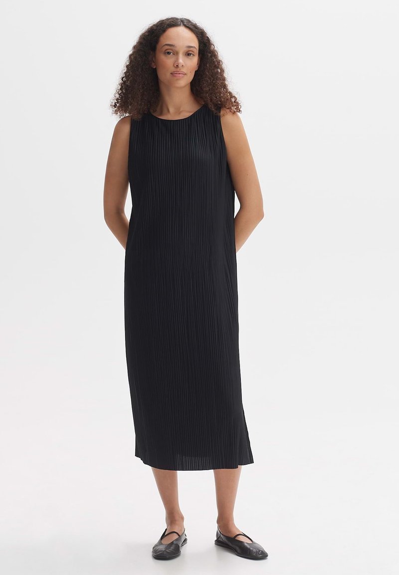 Black, sleeveless, pleated midi dress with a round neckline. The fabric is smooth, and the design features side slits for ease of movement.