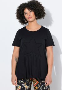 Sort kortærmet t-shirt med et tekstureret stjernedesign og frynsede detaljer forneden. Lavet af blødt, strækbart stof.