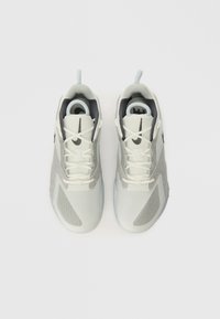 Lichtgrijze sportschoenen gemaakt van mesh en synthetisch materiaal, met zwarte accenten, veters en een afgerond te ontwerp.