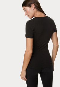 Czarny dopasowany t-shirt z krótkim rękawem i okrągłym dekoltem, wykonany z miękkiego, elastycznego materiału, zaprojektowany w taki sposób, aby podkreślać sylwetkę.